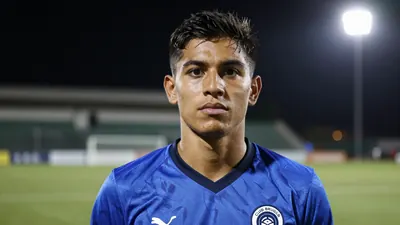 A 22-year-old Ecuadorian defender in a blue Club Brugge jersey, standing on a football pitch with a determined...