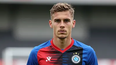 A determined 28-year-old Club Brugge midfielder, wearing the Blauw-Zwart's blue and red home kit with the club crest on...