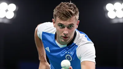 A tight action crop of a 21-year-old German player in a blue and white jersey, with a white ball at his feet, looking up...