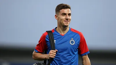 Mid-20s athletic midfielder, medium build, waist-up, wearing Club Brugge home jersey (blue body with red sleeves, crisp...