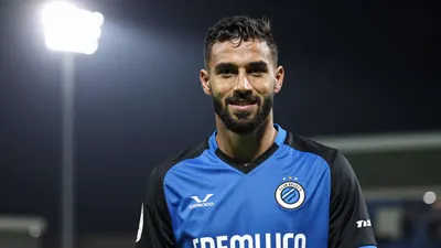 A 25-year-old, athletic, dark-haired, bearded, right-footed, Club Brugge defender, wearing a blue and black jersey made...