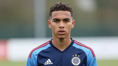 A tight crop of a young, anonymous player in a Club Brugge jersey, with a determined expression, standing in front of a...