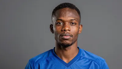 Photorealistic head-and-shoulders shot of a 21-year-old Gambian football player in a solid blue jersey, smooth fabric texture