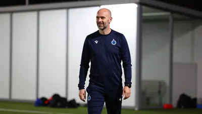 A photorealistic image of a 25-30-year-old, athletic-looking, balding, Club Brugge coach or assistant coach, wearing a...